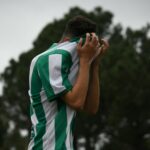 a soccer player covers his face with his hands